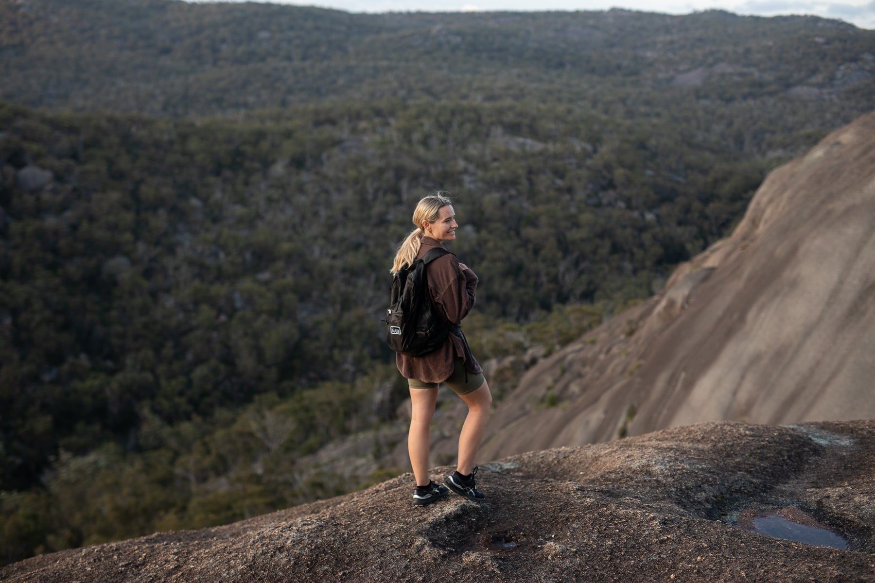 Person hiking with a Nakie foldable backpack overlooking a mountain landscape.