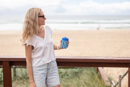 Woman holding an Ocean Breeze Cooler & Coffee Cup at the beach