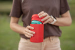 Red insulated coffee cup lid with turquoise band, held in hands outdoors preview #8
