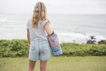 Sustainable down puffy blanket with coral and blue mandala pattern, shown rolled and carried over shoulder outdoors preview #7