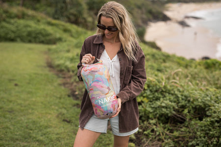 Sustainable down puffy blanket with multicolored watercolor snake design, displayed outdoors in carrying bag