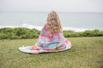 Multicolour tie-dye puffer blanket wrapped around person sitting on grass overlooking ocean preview #10