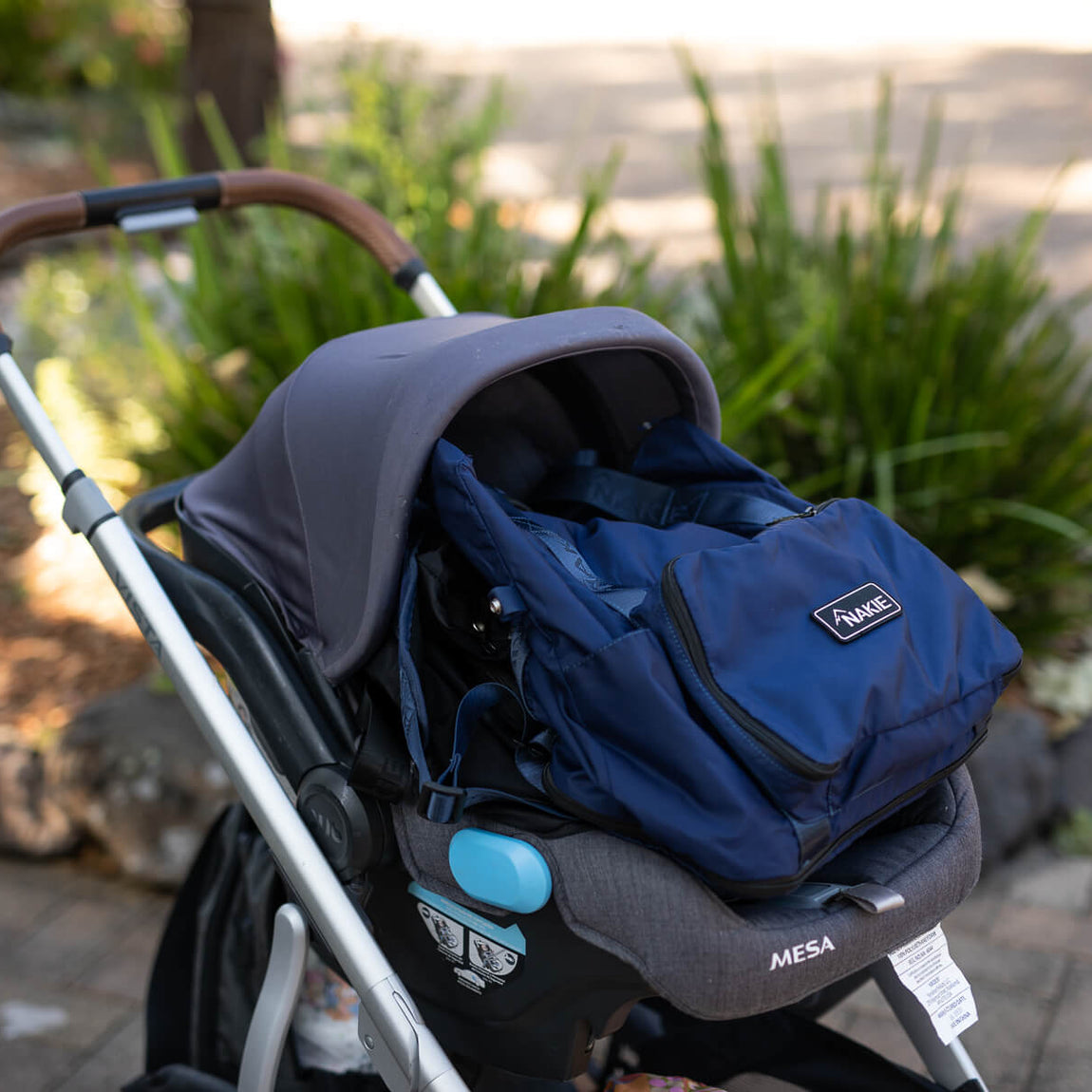 Navy quilted tote bag with handles attached to stroller, featuring branded label
