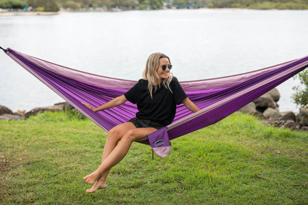 Woman laying in a purple Nakie hammock, highlighting the hammock's portable and easy-to-set-up features