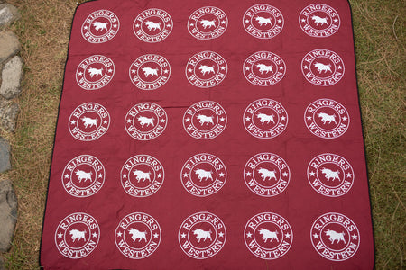 Burgundy picnic blanket with white Ringers Western logo and bull design repeated in grid pattern