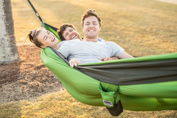 Green and gray recycled hammock with straps, three people lounging outdoors in natural setting